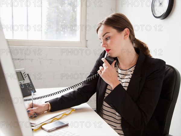 Young woman working in office talking on phone . Photo : Jessica Peterson