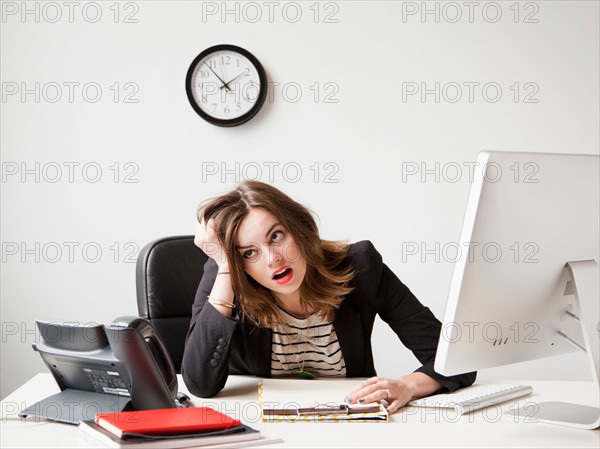 Studio shot of young woman working in office being under emotional stress. Photo : Jessica Peterson