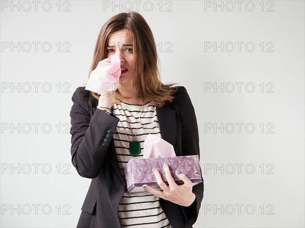 Studio shot of young woman sneezing. Photo : Jessica Peterson