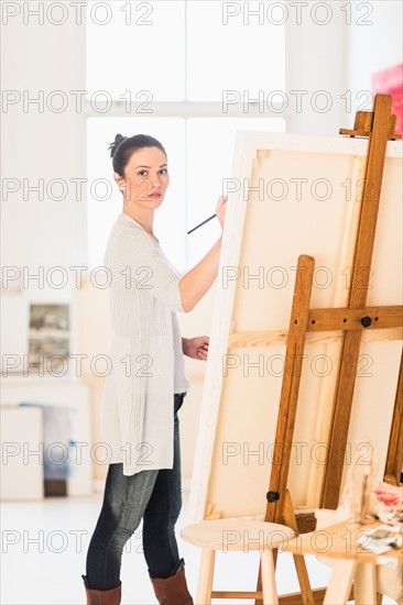 Woman painting at easel.