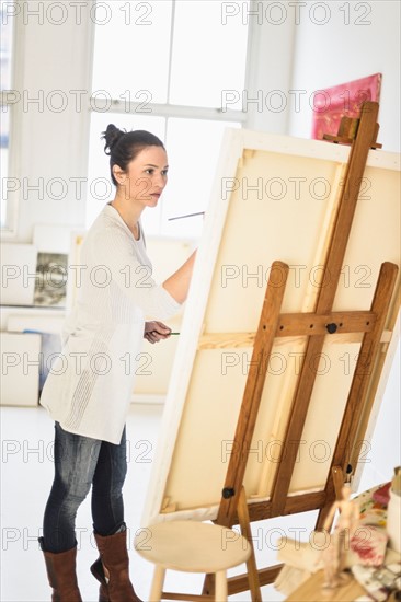 Woman painting at easel.