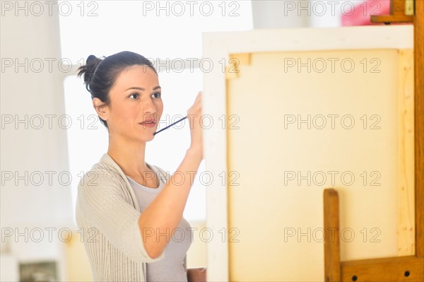 Woman painting at easel.