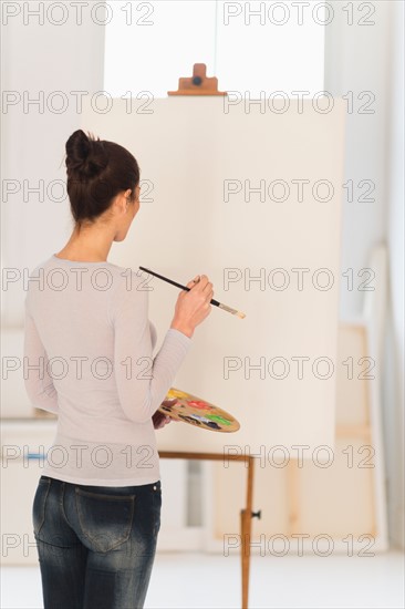 Woman painting at easel.