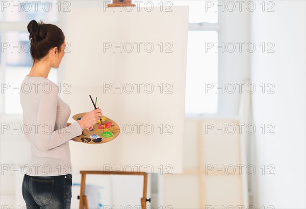 Woman painting at easel.