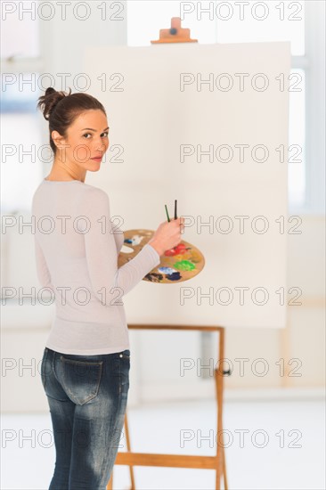 Woman painting at easel.