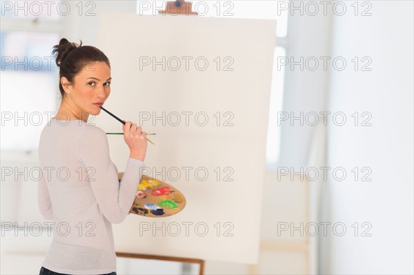 Woman painting at easel.