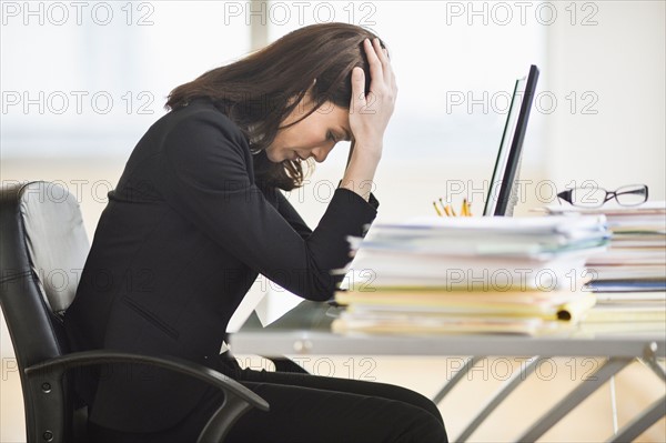 Businesswoman with head in hands.