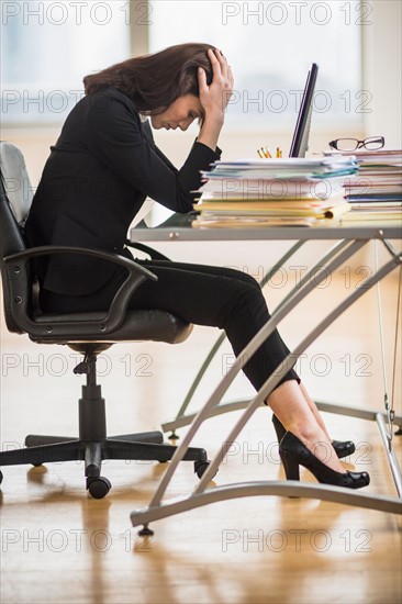 Businesswoman with head in hands.