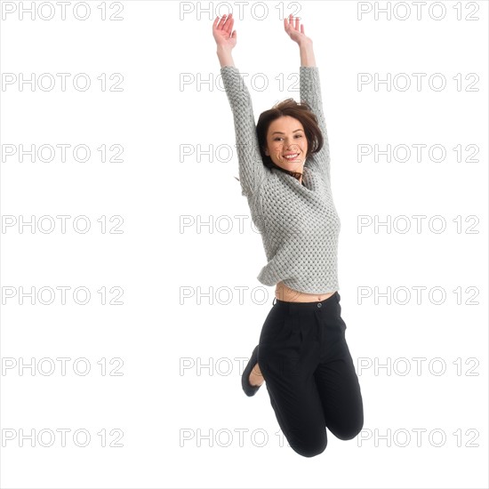 Studio portrait of mid adult woman jumping.