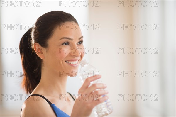 Woman drinking water in gym.