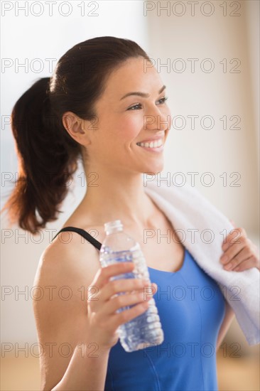 Woman drinking water in gym.