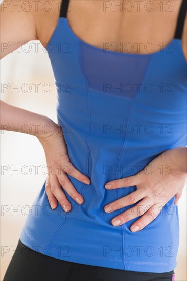 Midsection of woman with hands on back.