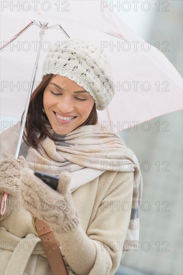 Woman with umbrella using phone.