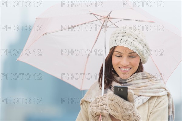 Woman with umbrella using phone.