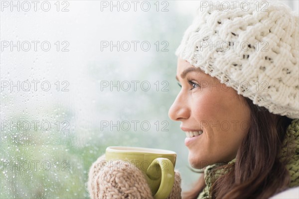 Woman in warm clothes holding mug.