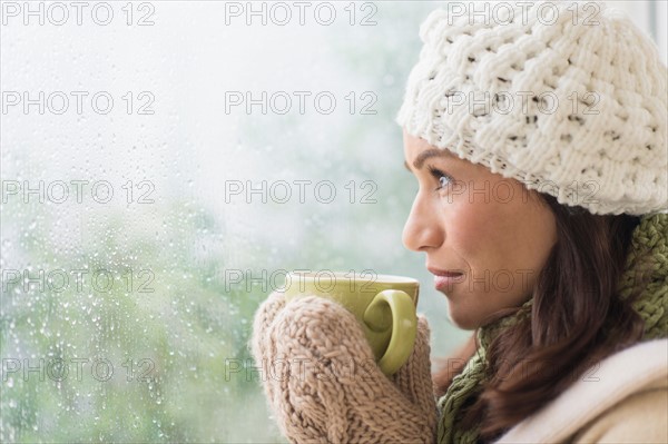 Woman in warm clothes holding mug.