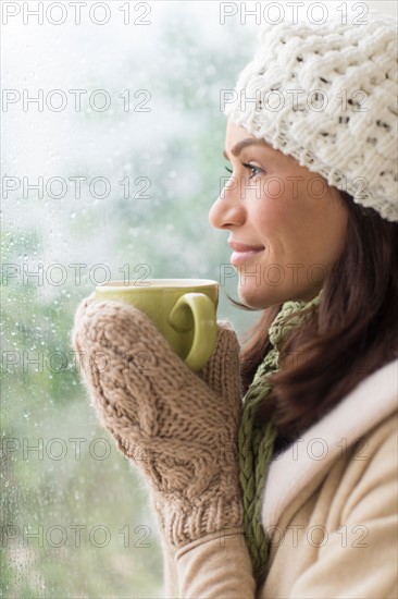 Woman in warm clothes holding mug.