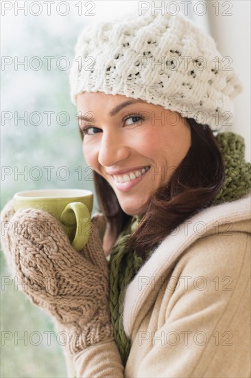 Portrait of woman in warm clothes holding mug.