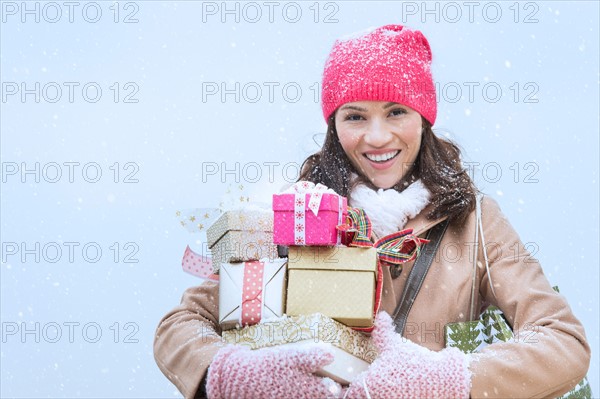 Portrait of woman in winter clothes carrying presents.