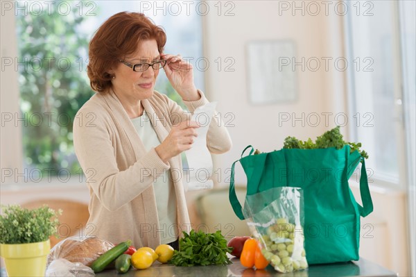 Woman reading shopping list in kitchen.