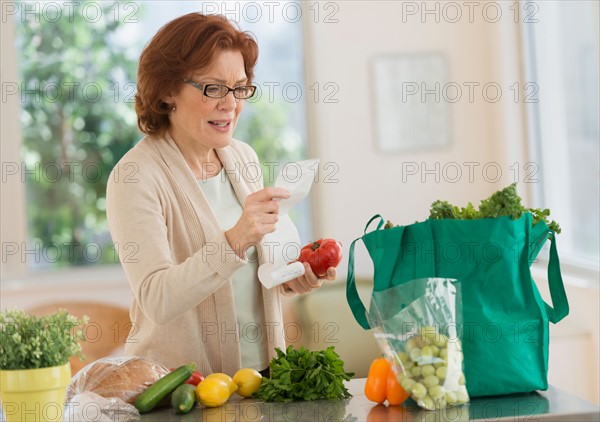 Woman reading shopping list in kitchen.