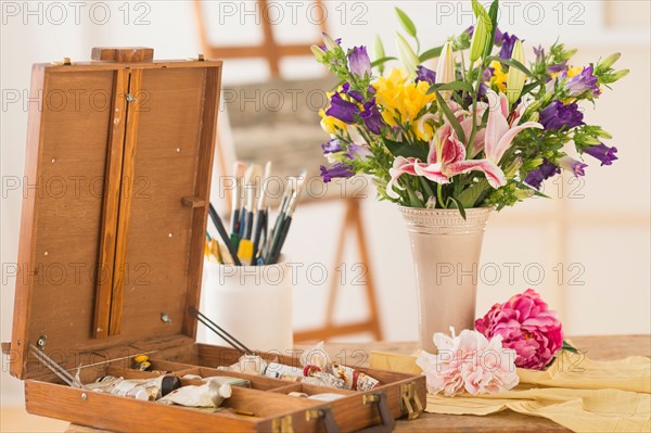 Still life with fresh bouquet and box of paints.
