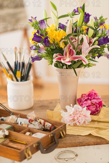 Still life with fresh bouquet and box of paints.