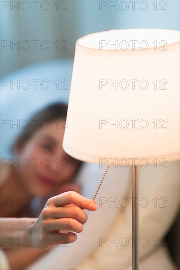 Woman turning off lamp.