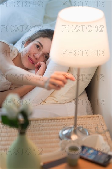 Woman turning off lamp.