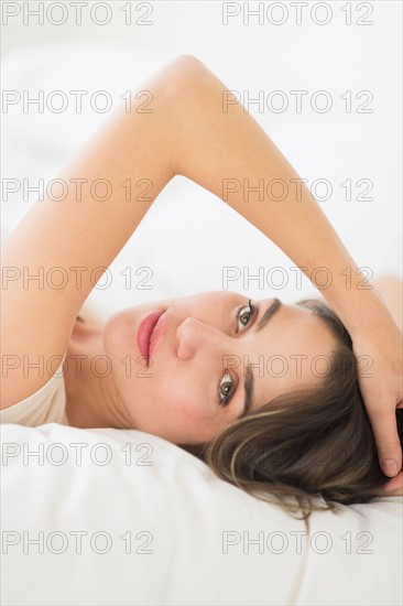 Portrait of young woman lying in bed.