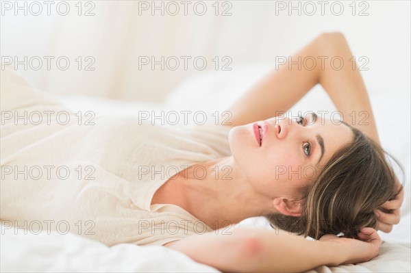 Portrait of young woman lying in bed.