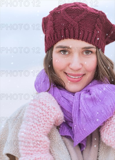 Portrait of young woman wearing knit hat, gloves and scarf.