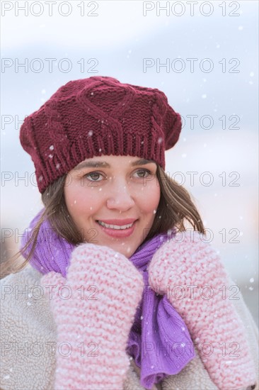 Portrait of young woman wearing knit hat, gloves and scarf.