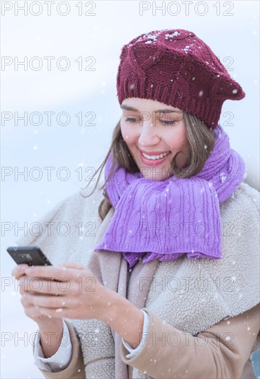 Young woman in wearing warm clothes and using mobile phone.