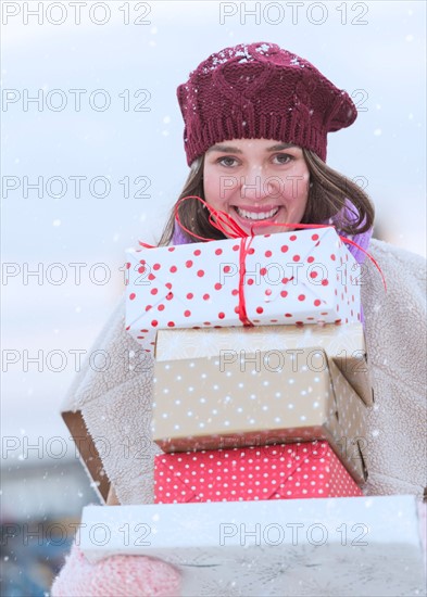 Portrait of young woman carrying stack of Christmas presents.