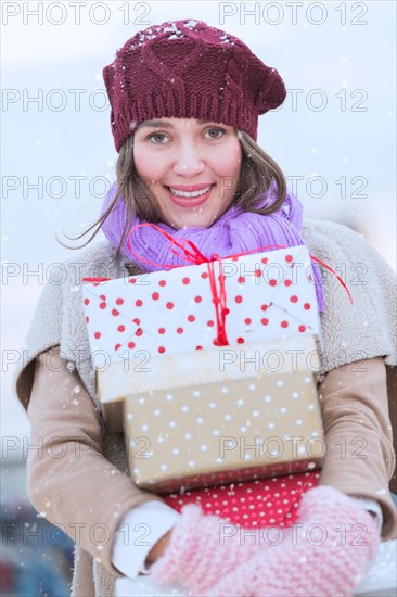 Portrait of young woman carrying stack of Christmas presents.