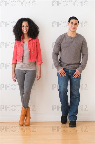 Smiling couple standing against white wall.