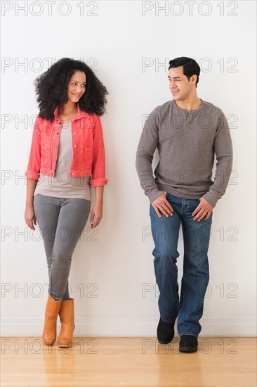 Smiling couple standing against white wall.