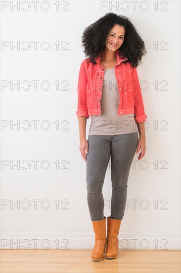 Portrait of smiling mid adult woman standing against wall.