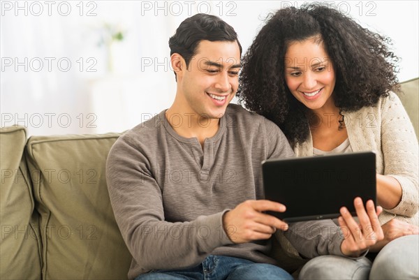 Couple using digital tablet on sofa.