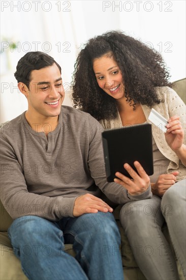 Couple using digital tablet on sofa.