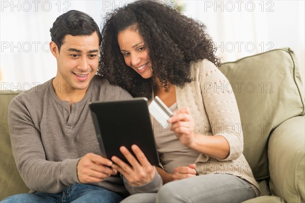 Couple using digital tablet on sofa.