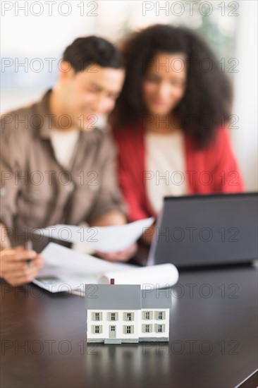 Smiling couple planning home ownership with model home.