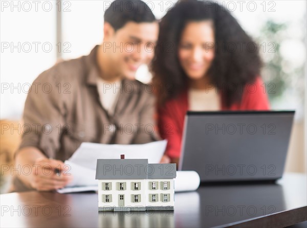 Smiling couple planning home ownership with model home.