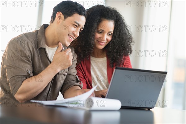 Smiling couple planning home ownership with model home.