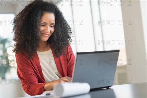 Smiling mid adult woman doing home finances with laptop.