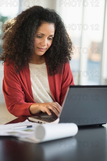 Smiling mid adult woman doing home finances with laptop.