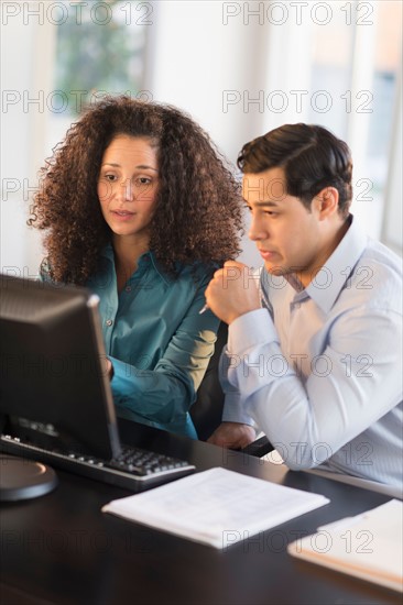 Man and woman working at desk in office.