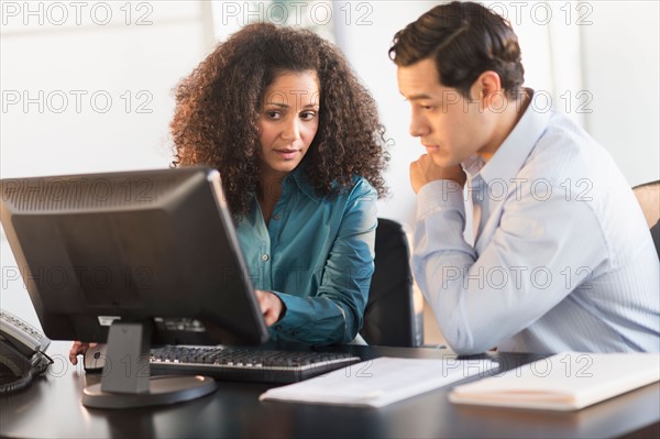 Man and woman working at desk in office.