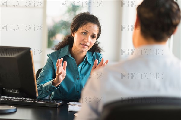 Woman interviewing man at desk.